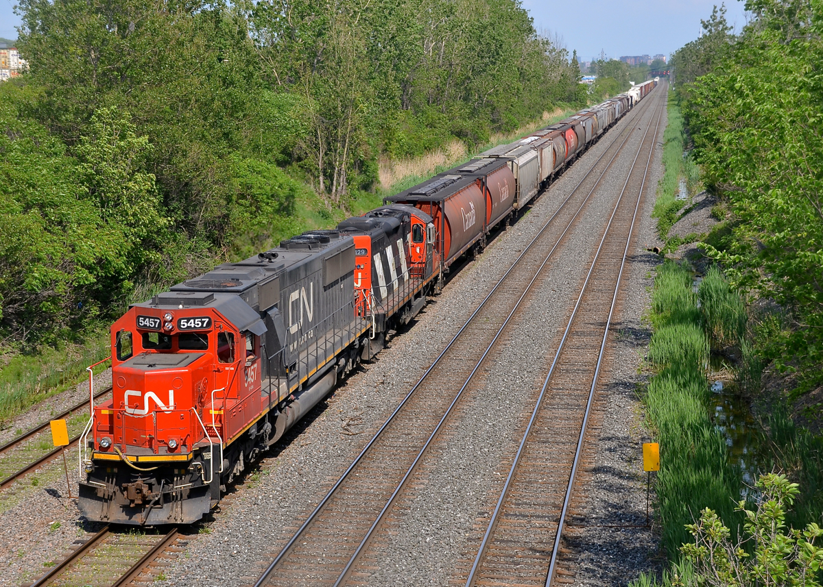 Big and small EMD. Two generations of EMD power (SD60 CN 5457 & GP9 CN 4129) lead CN 527 towards nearby Taschereau Yard on a very humid afternoon.