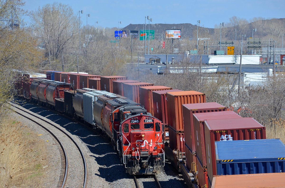 The Pointe St-Charles switcher heads west with a pair of GP9's (CN 7246 & CN 7015) with a cut of cars for Taschereau Yard as a very late CN 120 passes at right.