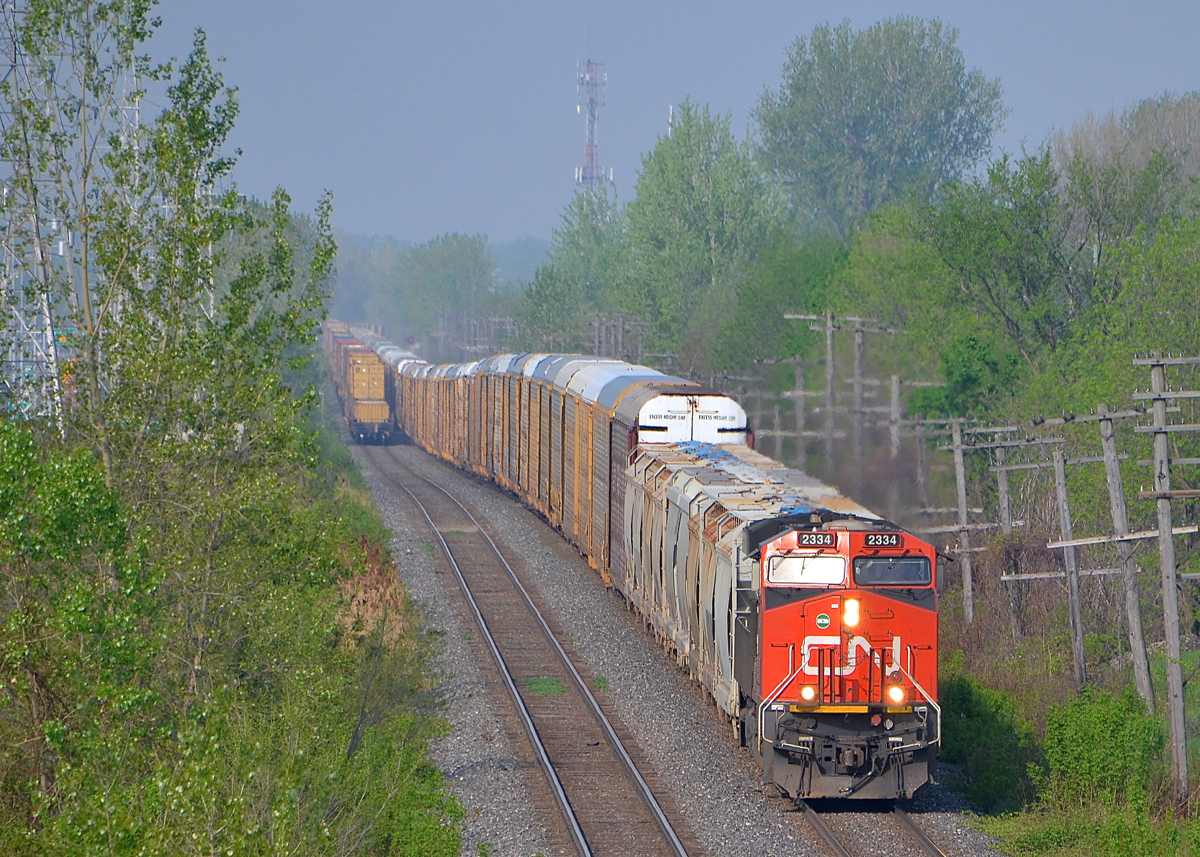 CN 372 heads east through Pointe-Claire after passing CN 14. This train is mostly autoracks and has CN 2334 headend and CN 2301 mid-train.