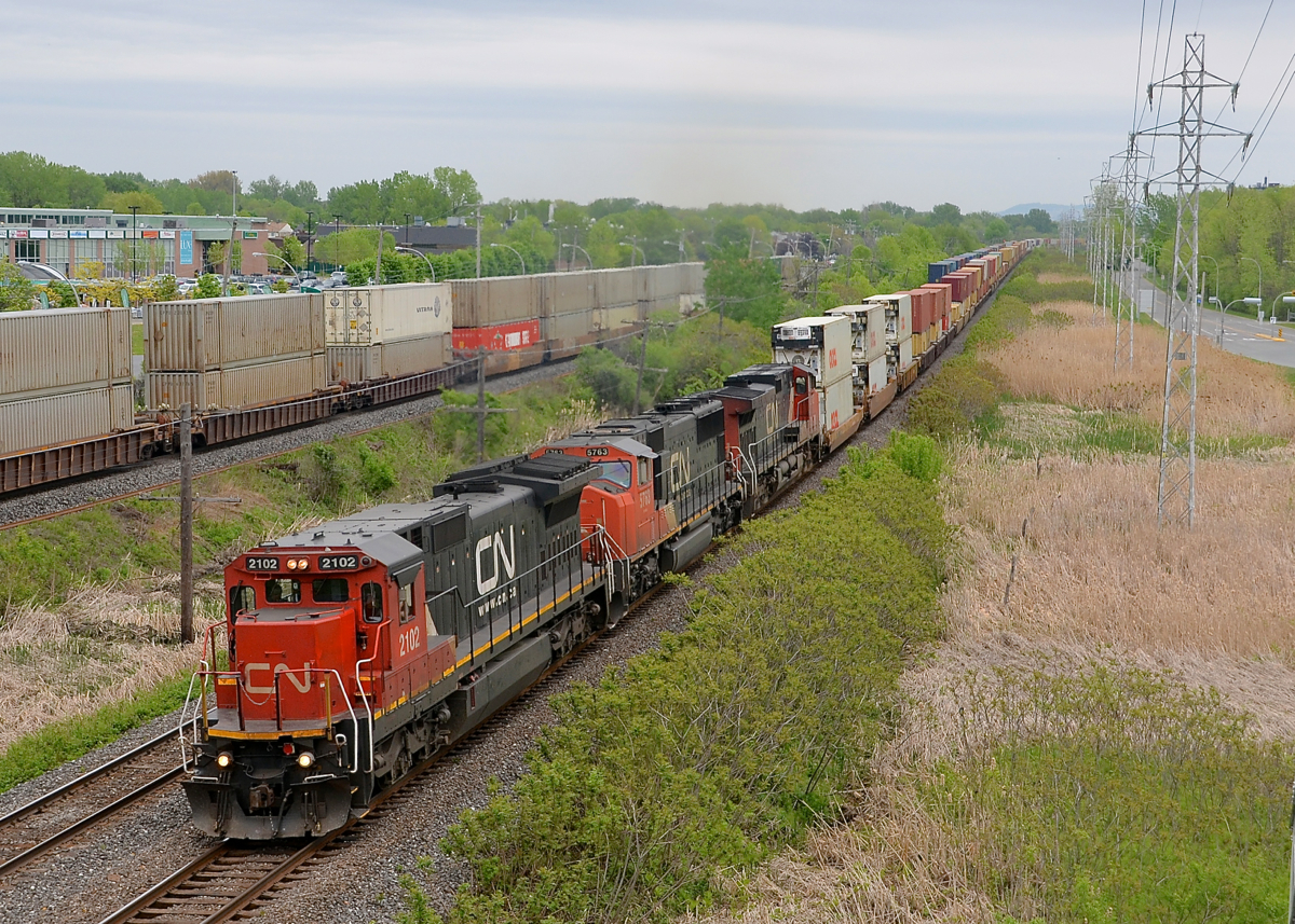 Three intermodal trains. CN 149 heads west through Pointe Claire with CN 2102, CN 5763 & IC 2712 on the south track of CN's Kingston sub. The tail end of CN 106 is on the north track and CP 112 is inbound at left on CP's Vaudreuil sub.