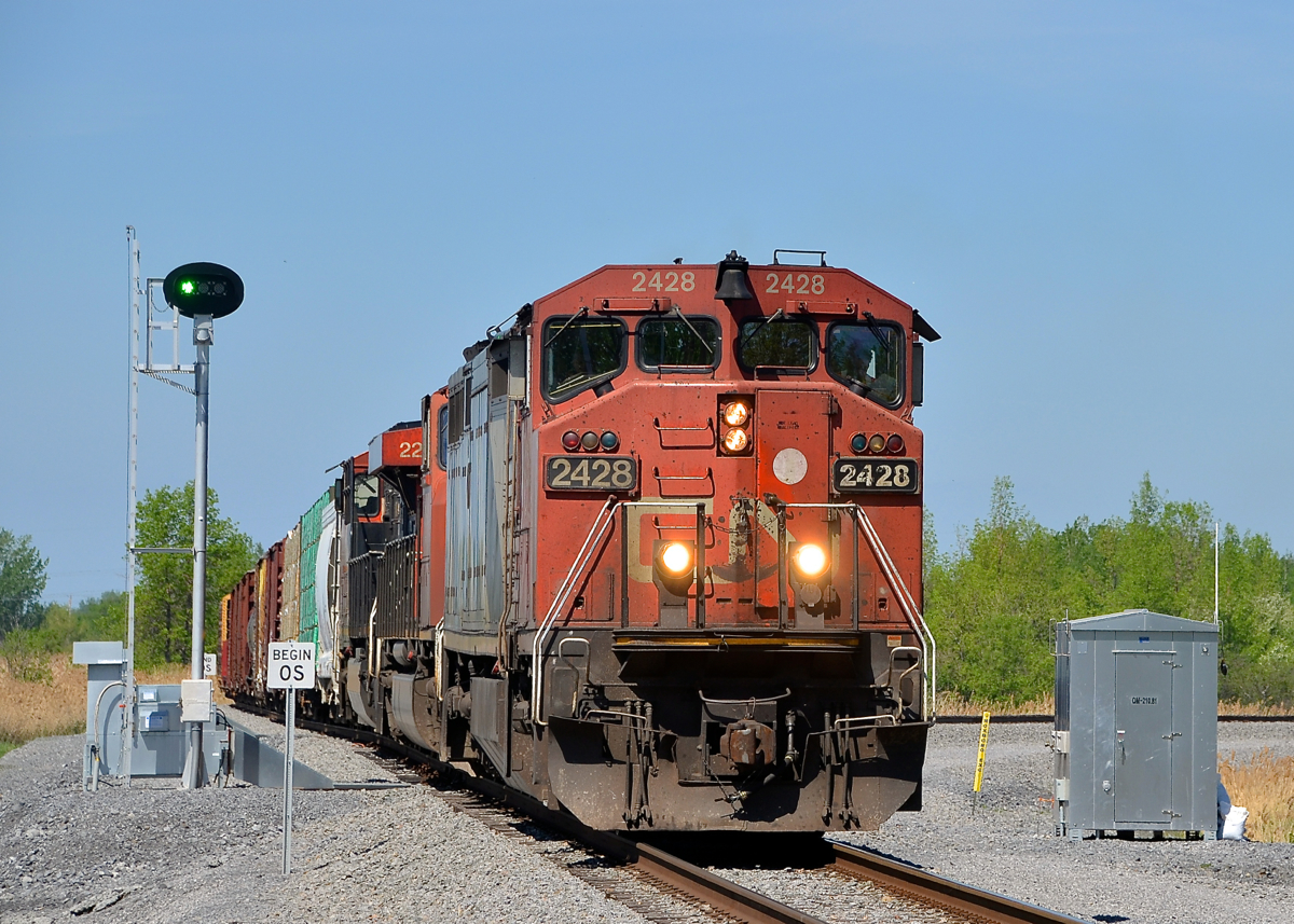 Passing a switch point indicator. CN 327 is passing a switch point indicator that I believe indicates over the radio whether the switch is lined for the main or the diverging route. CN 327 has CN 2428, CN 5643, CN 2230 for power and he is heading south after having to wait for the nearby Larocque bridge to lower after opening for a boat on the Beauharnois canal. He is heading to Huntingdon, Qc where a CSXT crew will take this train to Massena, NY and the CN crew will bring CN 326 to Montreal.