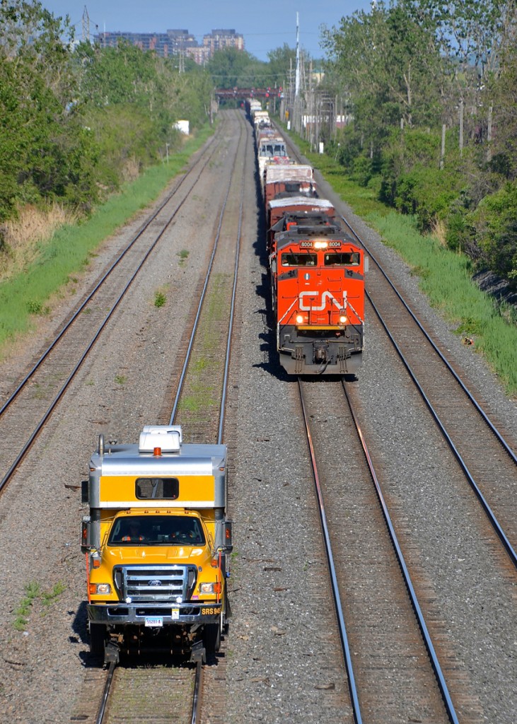 CN X321 and a Sperry truck (SRS 945) are both westbound on the Montreal sub near Taschereau yard. CN X321 has an all-GMD lashup of CN 8004, CN 4771 & CN 7502 (a hump unit returning from CAD).
