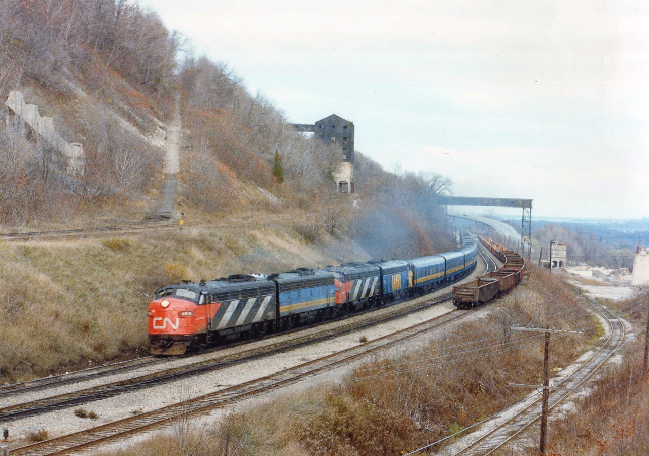 It is the day after the infamous Mississauga wreck. One CP train had come down to Hamilton in the morning in an attempt to bypass the Mess by making Toronto via the CN, and we hung around the day hoping to see a second one. But it didn't happen.  Dundas Station looked to be a nice spot to catch an eastbound. But since that opportunity became increasingly bleak as the day wore on, I decided to head for my 'perch', a mound of dirt on the south side of the tracks with a view of the old Canada Crushed Stone Ltd and wait for VIA #75. The evening was getting dull, resulting in an image not as sharp as I would have liked it; but this was a great lashup, even for those days. A-B-A-A combination. First and third units still in their CN paint, the others in the new VIA scheme. (This is the early days of VIA) Track on lower right went to Steetlys, another rock business; it connected with CN and the TH&B !!  Long gone, and there is a housing development there now...........