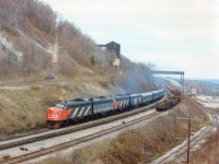 It is the day after the infamous Mississauga wreck. One CP train had come down to Hamilton in the morning in an attempt to bypass the Mess by making Toronto via the CN, and we hung around the day hoping to see a second one. But it didn't happen. Dundas Station looked to be a nice spot to catch an eastbound. But since that opportunity became increasingly bleak as the day wore on, I decided to head for my 'perch', a mound of dirt on the south side of the tracks with a view of the old Canada Crushed Stone Ltd and wait for VIA #75. The evening was getting dull, resulting in an image not as sharp as I would have liked it; but this was a great lashup, even for those days. A-B-A-A combination. First and third units still in their CN paint, the others in the new VIA scheme. (This is the early days of VIA) Track on lower right went to Steetlys, another rock business; it connected with CN and the TH&B !! Long gone, and there is a housing development there now...........