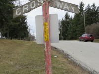 Juxtaposition. This well weathered crossing sign was likely installed long before anyone thought of 1-800 phone numbers.