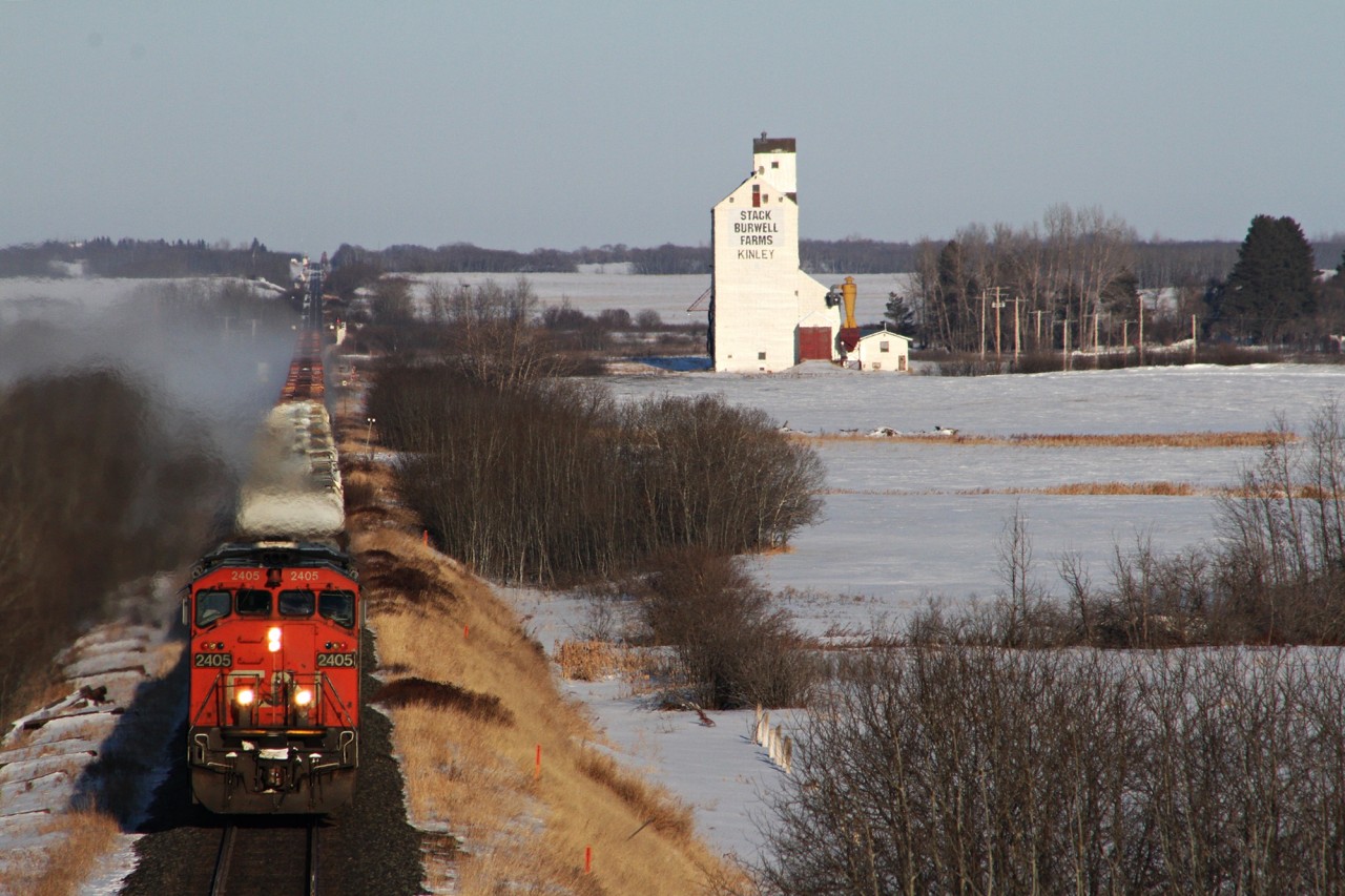 CN's sail boat train 347 with manifest traffic up front and empty centerbeams on the rear pass by the old Saskatchewan Wheat Pool at the villiage of Kinley.