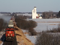 CN's sail boat train 347 with manifest traffic up front and empty centerbeams on the rear pass by the old Saskatchewan Wheat Pool at the villiage of Kinley. 