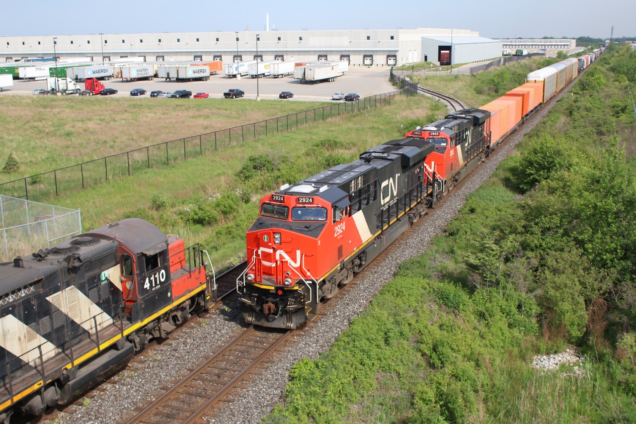 Old meets new! CN train #327 with a pair of clean GEVOs meets local #547 with a pair of veteran GEEPs at Milton. The local is trying to stay cool in the shade provided by the James Snow Parkway bridge, while waiting their turn to run around their train and head back to Aldershot.