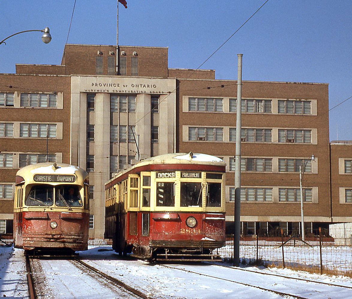 The Toronto Transit Commission needed to change their routes south of Union Station in 1961 when the Gardiner Expressway was being built. The TTC built the Ferry Loop in 1961 and used it for turning streetcars until Sept. 1965, on the site of the former Harbour Yard that used to have tracks installed to store streetcars from Eglinton Carhouse in the 50's. Pictured here, Peter Witt car 2834 (a "Small Witt" originally built by the Ottawa Car Company, signed up for the Parliament route) and newer PCC 4518 (on the Dupont route) sit at Ferry Loop, in front of the large Government of Ontario Workmans Compensation Board building in background on Harbour Street. It became the OPP headquarters in 1973, and was demolished in 2011.  By this day, the end was near for the Witt cars in regular service. The Dupont streetcar route on Bay was discontinued and replaced with buses roughly a month later, when the University subway line opened on February 28th 1963. The remaining Witts saw little service as spares for the next year or two until being officially retired on January 1st, 1965.