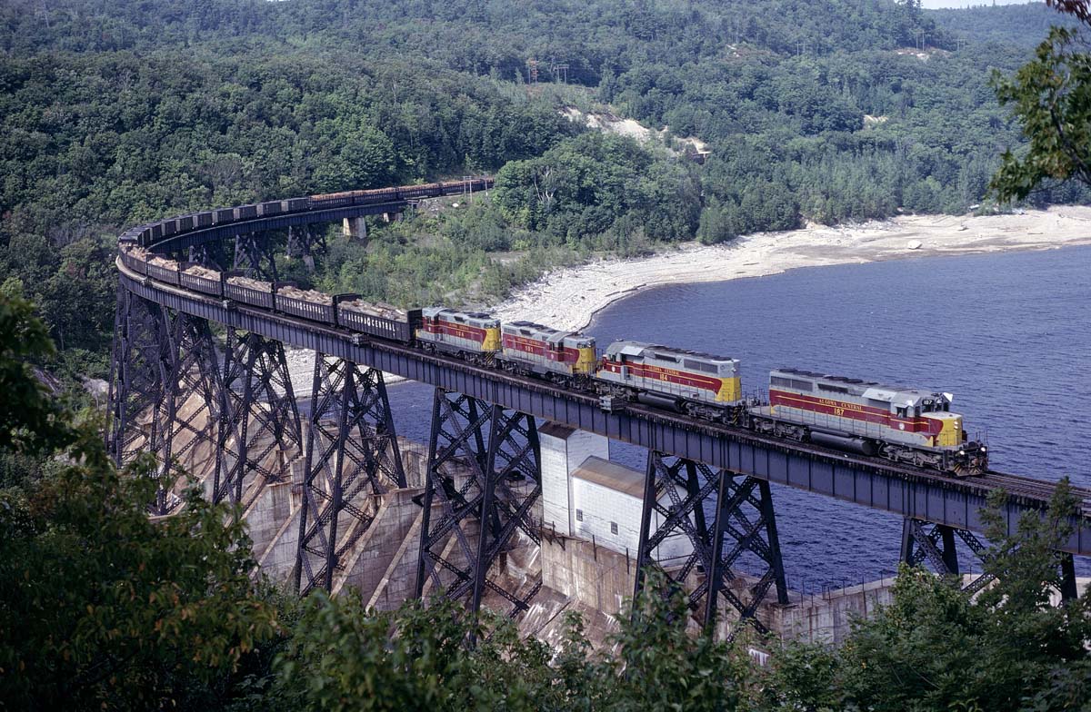 One of the scenic highlights of the Algoma Central Railroad is the bridge over the hydroelectric dam at Montreal Falls.  For our Labor Day weekend in 1981, several of us arranged with the power company for permission to drive back their private road to hang out and get a few shots at the dam. Once we were back there, one of the employees volunteered that the view was even better from on top of the little cabin they had there.  So here's a southbound freight with 2 SD-40-2's and 2 GP7L's and lot of logs on the head end crossing over the Montreal River.
