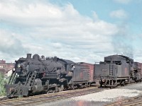 A couple of Consolidation-types work near downtown Pembroke, circa 1959.  Both of these 2-8-0 locomotives were built by MLW.  #2533 was built in 1906, while sister #2646 arrived two years later.  Their days were certainly numbered when Del captured this image.
