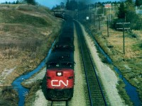 In my own experience, the late 1970s was a golden age for passenger train lashups. Here is a nice example. CN 6782 leads 3100, 3107 and 4102 as train #75 west with 15 coaches in tow; cresting that long grade from Bayview, some 10 miles distant. The image is taken from the new Hwy 52 overpass; one can see on each side of the lead unit remnants of the old grade crossing that was closed @1975. In the background is the old Inksetter Road bridge. This is Copetown? Yep. Sure doesn't look like this any more !!