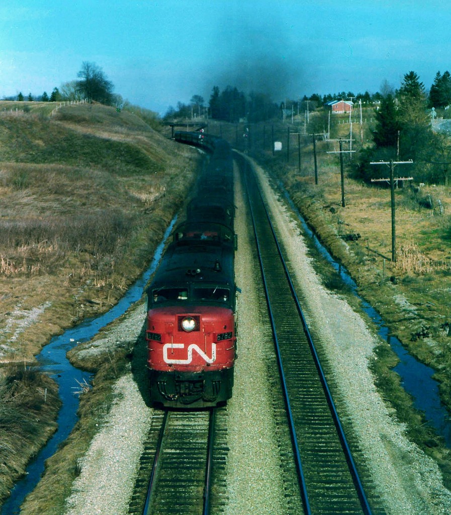 In my own experience, the late 1970s was a golden age for passenger train lashups. Here is a nice example. CN 6782 leads 3100, 3107 and 4102 as train #75 west with 15 coaches in tow; cresting that long grade from Bayview, some 10 miles distant. The image is taken from the new Hwy 52 overpass; one can see on each side of the lead unit remnants of the old grade crossing that was closed @1975. In the background is the old Inksetter Road bridge. This is Copetown? Yep. Sure doesn't look like this any more !!