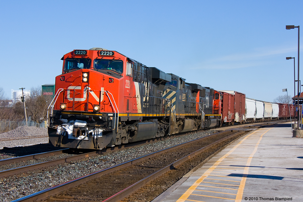 On a sunny winter afternoon, 149 rounds the bend past Cobourg station with a mix of CN and BC Rail power.
