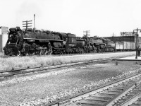 Doubleheading CN Northerns 6233 and 6259 wait to be cleared to cross the diamond northbound on the CN Brampton Sub (later renamed the Weston Sub), at West Toronto Junction on a sunny June day in 1958 (about 16:00 hours). In tow is a freight with a single stock car visible behind the power, and single and double door boxcars, the latter of which was still the primary means of transporting automobiles by rail. On the right an individual and baggage cart on the platforms of CPR's West Toronto Station can be seen, and the Galt Sub. In the background is the old Viceroy Rubber factory off Dupont Street. <br><br> At the time, the linkage rods along the Galt Sub track and by the station that control signals and switches signify the diamonds were still controlled by the old West Toronto interlocking tower just to the north, visible <a href="http://www.railpictures.ca/?attachment_id=16093"><b>*here*.</b></a> A few years later in 1965, the whole area would be converted to CTC, controlled by CP, and the tower demolished. A view of the diamonds then can be seen <a href="http://www.railpictures.ca/?attachment_id=15874"><b>*here*</b></a>. Today, GO Transit MP40's hauling bilevels, VIA corridor trains and Union Pearson Express DMU's replace the CNR Northerns, freight trains, GMD1-hauled commuter trains and RDC's of yesteryear on the Weston Sub.