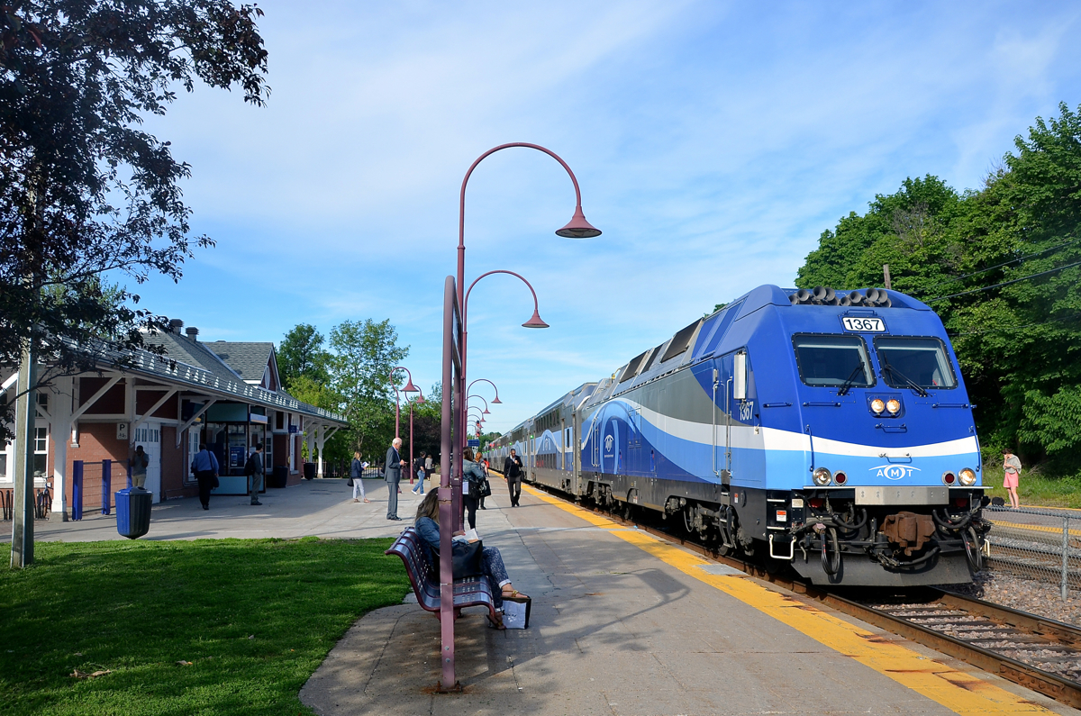 The start of another work day. In a scene played out in hundreds of towns across North America every weekday morning, a commuter train is arriving to take people downtown. In this case AMT 112 from Hudson is bound for downtown Montreal as it passes Montreal West Station with dual mode engine AMT 1367 leading. In a few seconds the train will stop and more passengers will board.
