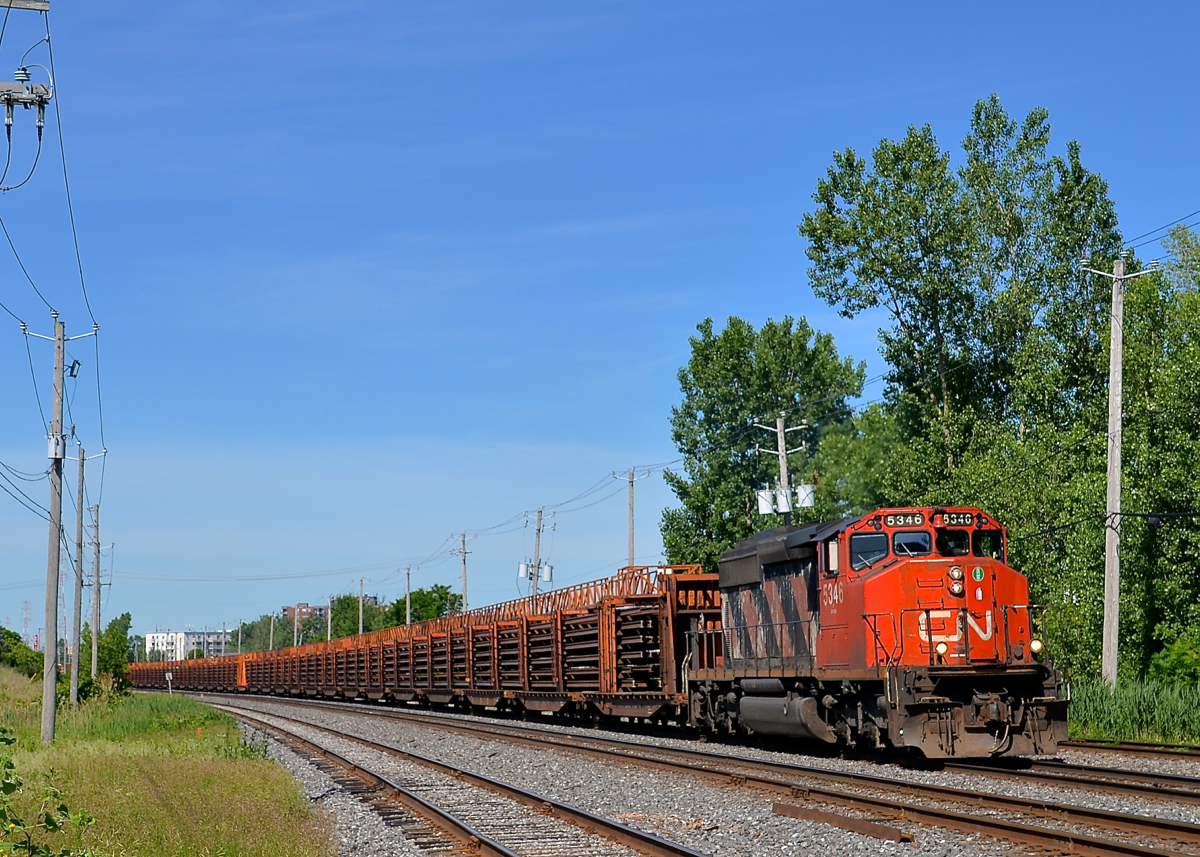 A solo SD40-2W on a rail train. CN 5346 is the sole power on CN 486, a loaded rail train bound for Edmunston, NB that is passing through St-Lambert. At the tail end of the train is mixed freight.