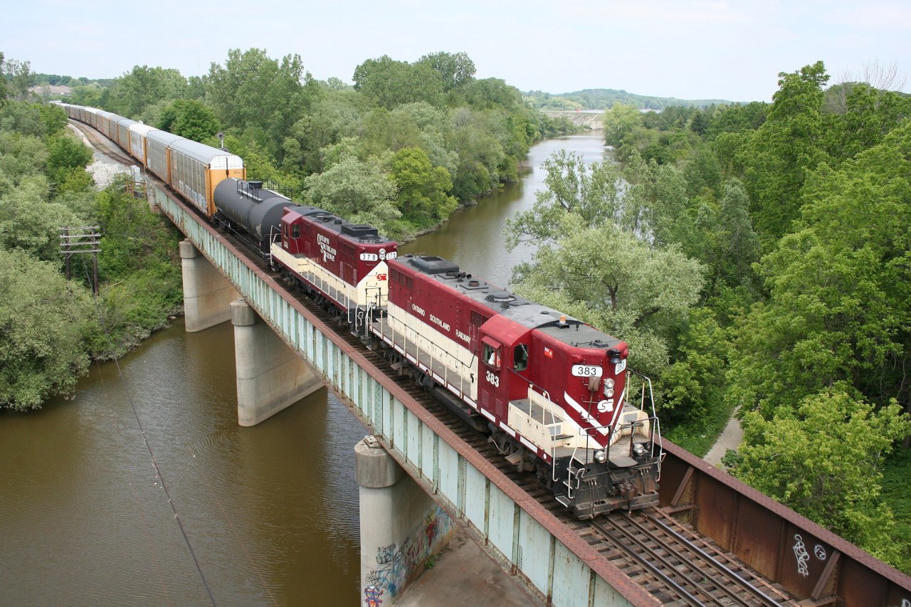 Ontario Southland GP7s 383 and 378 rumble across the Thames River bridge in Woodstock with a collection of empty autoracks for the CAMI car plant in Ingersoll.