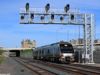 A westbound Union Pearson Express train charges at about track speed past the Etobicoke North GO Station on its way to Pearson Airport.The station used to stand on the south side of the tracks, and the old station depot still stands with dust covering. With the opening of the Union Pearson Express, which opened the day of the photograph, the station had to be transferred over to the north side of the tracks since the UPX would use the 2 south tracks, as the spur to the destination to Pearson Airport is about a mile down the tracks and crossing over with plenty of GO Trains and other rail transport will be quite challenging and will cause plenty of delays.