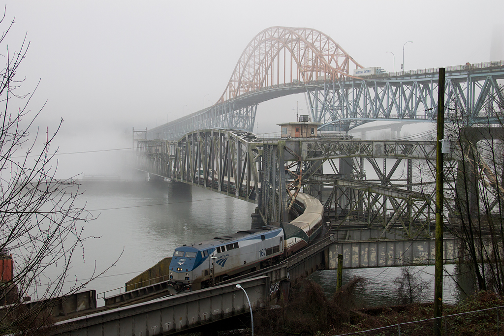 Amtraks daily Cascades from Seattle heads northbound across the historic Fraser River Bridge, on its way towards Vancouver, BC. High above the rail bridge is the aged Pattullo road bridge.