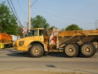 Something you don't see every day....a Volvo A35D Articulated Dump Truck waits patiently for 496 to clear the crossing with QGRY 2301 and 4 hoppers