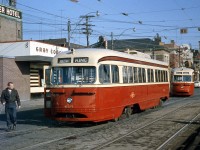 A pair of Toronto Transit Commission PCC cars wait at the start of The Queensway to turn into the TTC's Roncesvalles Carhouse, at the intersecting junction where King Street, Queen, Rocesvalles and The Queensway all come together in an interesting arrangement. Car 4215 was out on a King run, and 4232 behind signed up Queen. Another PCC is also visible along Queen St., lined with storefronts advertising for CIBC, the Royal Bank of Canada, and Pickin' Chicken BBQ.
<br><br>
Behind the 4215 is Gray Coach Lines' Sunnyside bus terminal. GCL was an interurban coach operator owned by the TTC, with many routes branching out from Toronto to places as far as London, Owen Sound, and North Bay, advertising "Travel The King's Highway" and other travel information in neon lighting on its facade. Part of the nearby Edgewater Hotel's signage (today a Howard Johnson) is visible on the left behind the GCL terminal (now a McDonalds). The old CNR Sunnyside Station is out of view to the right.
