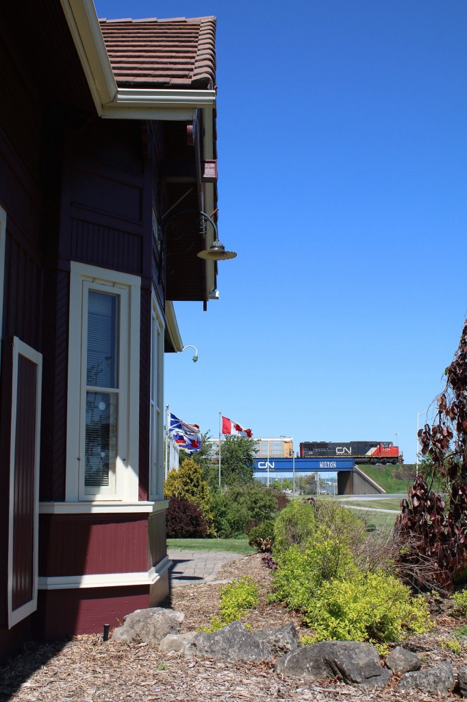 Canadian National's route through Milton can be traced back to its Branchline routes when it was part of the North & northwestern RR operating between Port Dover and Allandale as well as a line to Collingwood. CN' s take over of the bancrupt N&NW in the 1920s would lead to gradual abandonment of most of the lines except for the section between Burlington West and Georgetown. This section would become part of the new route to CN's new Mac Millian yard in North Toronto. The old yard in Mimico by this time was too small and too congested. In Milton the old N&NW route was relocated to the towns west side and it was also elevated to avoid congestion in town. The old station in town was saved and relocated when the original right of way through town was downgraded. Abandonment of the old line through town came in the 1980s. Here we see CN train 332 on the new elevated section passing the relocated station.