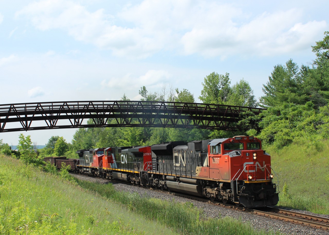 CN 8897 leading CN 2593 and CN 2195, put the power to the tracks as they head under the Glencairn Golf walk bridge just before MM30 on the Halton Sub with a mixed load of boxcars, gondolas, and ethanol cars.