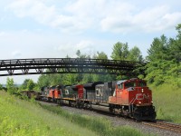 CN 8897 leading CN 2593 and CN 2195, put the power to the tracks as they head under the Glencairn Golf walk bridge just before MM30 on the Halton Sub with a mixed load of boxcars, gondolas, and ethanol cars.