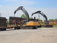 Two large John Deere 350G loaders lift a large section of prefabricated track section off a rail car on the siding at MM32.2 on the CN Oakville sub. They lifted the section up and the truck crew moved the rail car out of position so they could move the section to its destination behind them.