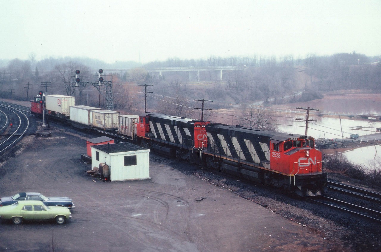Again, I am out on a damp drizzly morning. Waiting up on the hillside at Bayview Jct for something to happen. After an hours' restlessness, along comes this move. CN 2528,2552 with 3 cars and a caboose. Since I do not have any notes from back then regarding trains or train numbers to and from Niagara, I have no idea what this move was. It has been suggested a transfer to the Hamilton yard facility. Sounds right. So why isn't this handled by a couple of SWs as I was used to seeing? Anyway, this is the "train" of the morning, The 2528 became 3538, was sold to NRE...I'm wondering where it is now......the second MLW M-420(W) 2552 was retired in 1984. Why am I out on such a dreary morning? It was my day off work. You take what you can get.