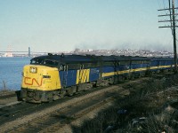 Via Rail FPA-4 6763 leads train #15 past what's now known as Birch Cove Marine Park which is located at the west end of Rockingham Yard. The train is travelling alongside the Bedford Basin, that the A. Murray McKay bridge between Halifax and Dartmouth in the background. 