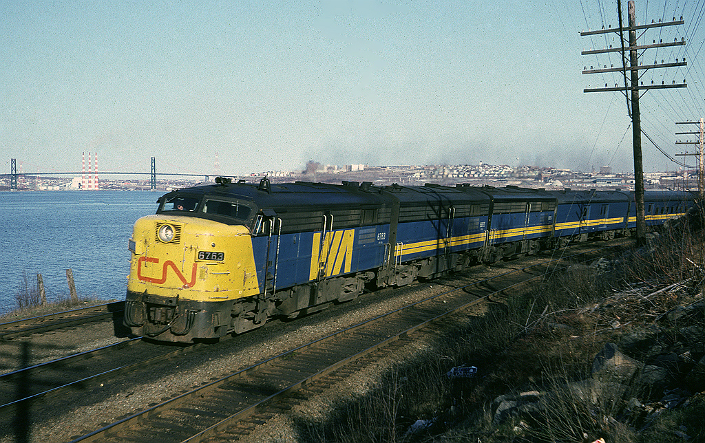 Via Rail FPA-4 6763 leads train #15 past what's now known as Birch Cove Marine Park which is located at the west end of Rockingham Yard. The train is travelling alongside the Bedford Basin, that the A. Murray McKay bridge between Halifax and Dartmouth in the background.