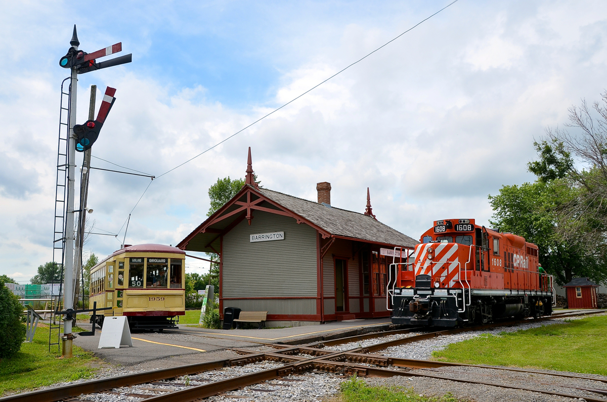 CP 1608 is running long hood forward after heading to the Des Bouleaux spur to do some tree trimming and has just cleared the diamond in front of Barrington Station at Exporail. MTC 1959 is finishing its station stop and will soon continue its trip around the museum grounds.