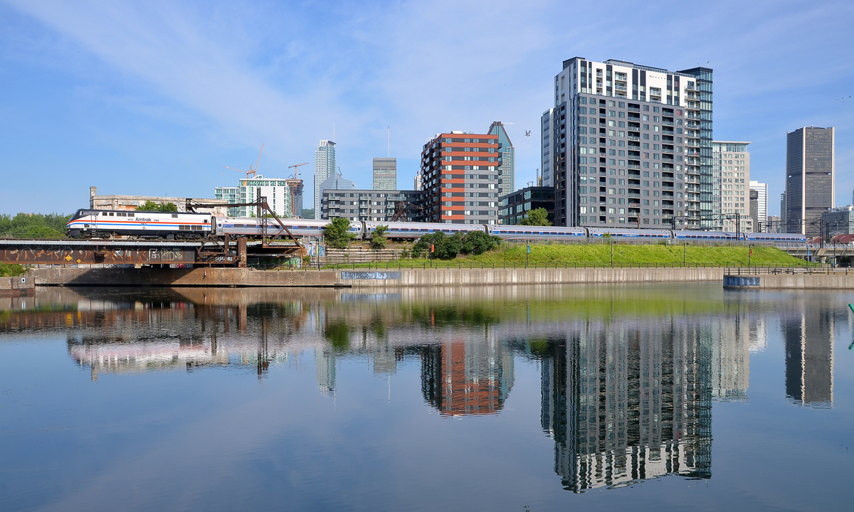 Amtrak heritage, reflected. The southbound Adirondack deadheads towards Montreal's Central Station with heritage unit AMTK 145 pushing, castings its reflection in the Peel Basin along with Montreal's skyline.