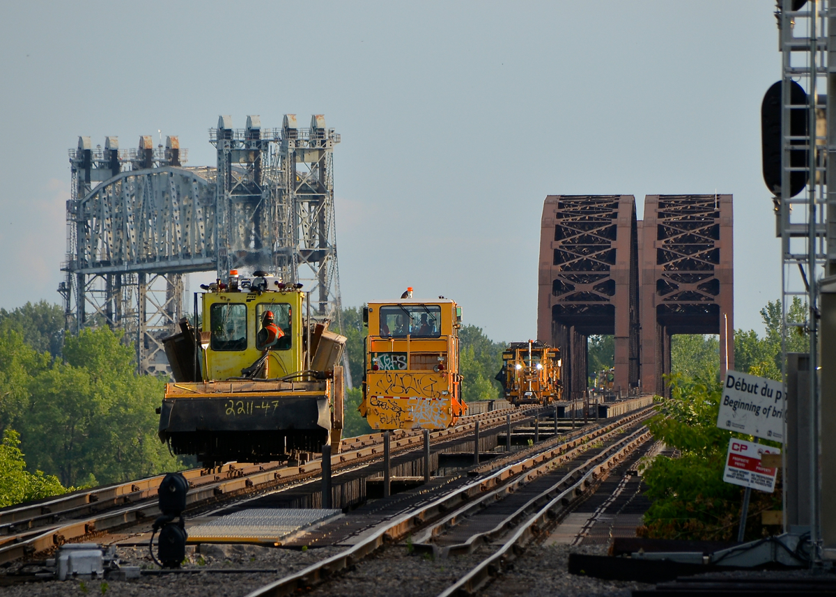 A track gang is leaving the island of Montreal and Lasalle Yard to work on the CP Seaway spur on the south shore. They are crossing the St-Lawrence river but will have to wait for the Seaway bridge at left to go back down before they can continue.