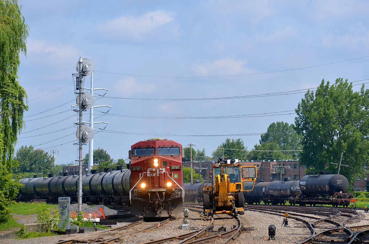 CP 550 is passing a Pettibone speedswing (CP 5510-33) in the Lasalle yard with CP 8797 leading and CP 8762 at the tail end. At right is a cut of tank cars, including a damaged one on a flat car (presumably going to CAD, which is nearby).