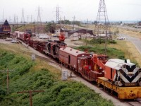 The CN made news for themselves around the Golden Horseshoe back in 1978. Three nasty wrecks within a few months. One at Grimsby preceded another biggie at Stoney Creek by 9 weeks.  At Grimsby, 29 cars of 76 on a westbound #387 hit the skids June 29th just before Maple Av overpass; scattering railcars and blocking both main tracks. This image, taken looking west off that same overpass, shows the CN worktrain on the scene, rolling up to the Grimsby Station. (The derailment a few hundred yards to the east of this image) CN geeps in consist are 4520 and 4509. The station had just undergone renovations and now earned its keep as "Village Depot", a cluster of freight cars posed as "shops" as well as a Keystone Kellys restaurant in the main building. A shoo-fly track is occupied opposite the station, and on the left is the offload track that used to service the old GTR station & other industry many years ago. The GTR station, just out of view, is one of the oldest in Canada and functions now as a Pottery & Antique business.