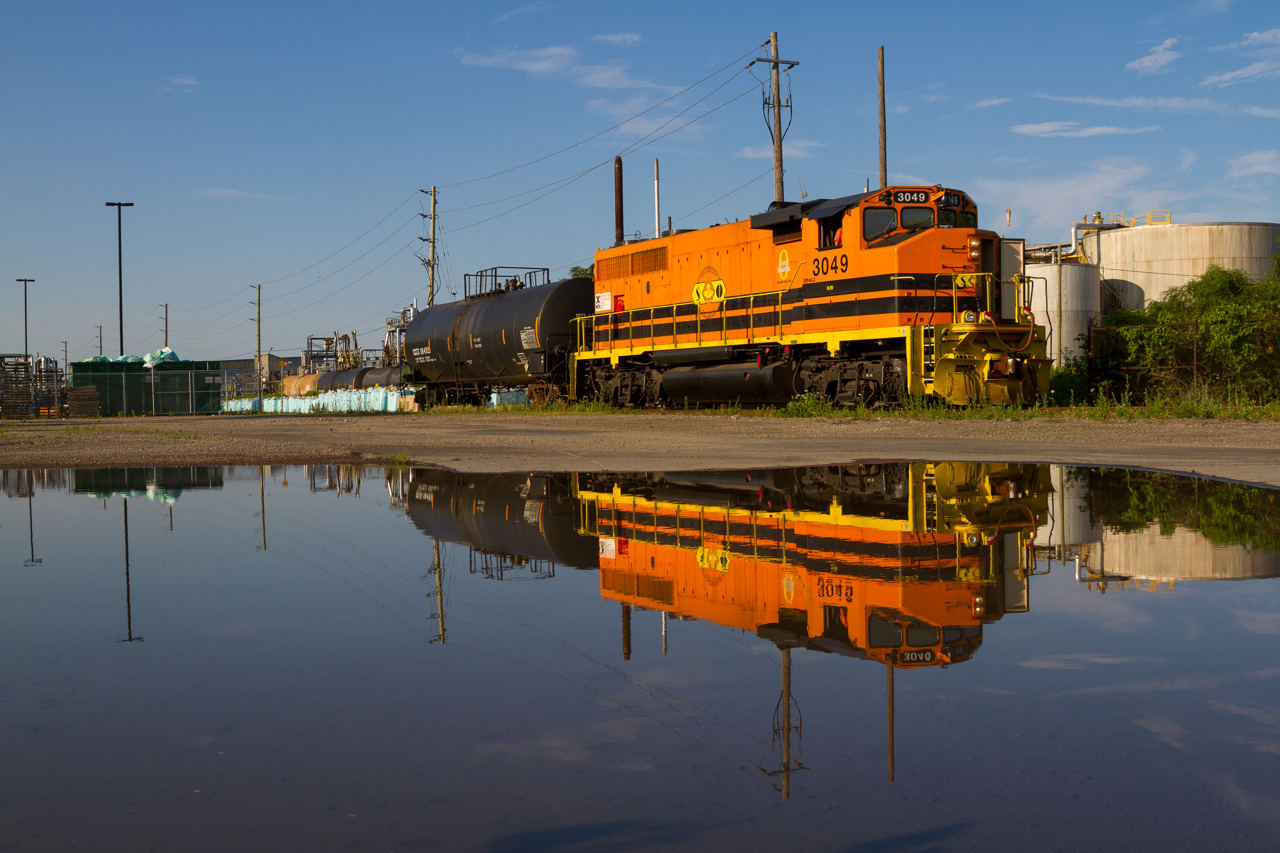 Thanks to rain fall the day previous, RLHH 3049 is seen casting a near perfect reflection as they spot a single tank car from one of Hamilton's many harbour-side industries.