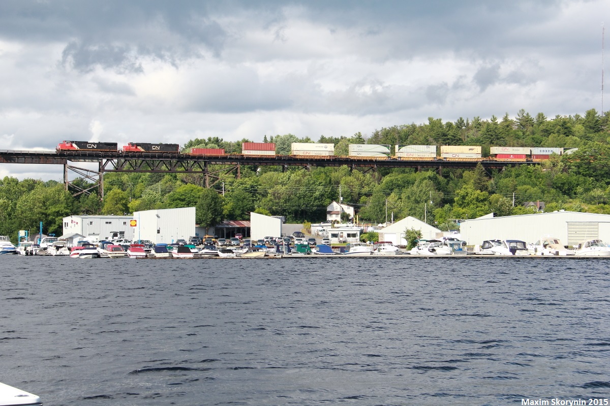 Train Q10531 with 2556 leading Illinois Central 1036 (in CN paint) as it passes over the Parry Sound trestle in town with the Canada Day festival happening in town. The trestle was built in 1907 and spans the 517m gap over the Seguin River 32m high.