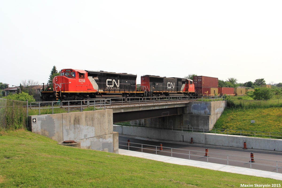 Canadian National intermodal train Q14891 with CN 5258 leading the way, a unique SD40-2W locomotive which was a former LNG test unit and a SD75I locomotive trailing as they speed past the New Westminster Drive underpass shot from Gilmore Park.