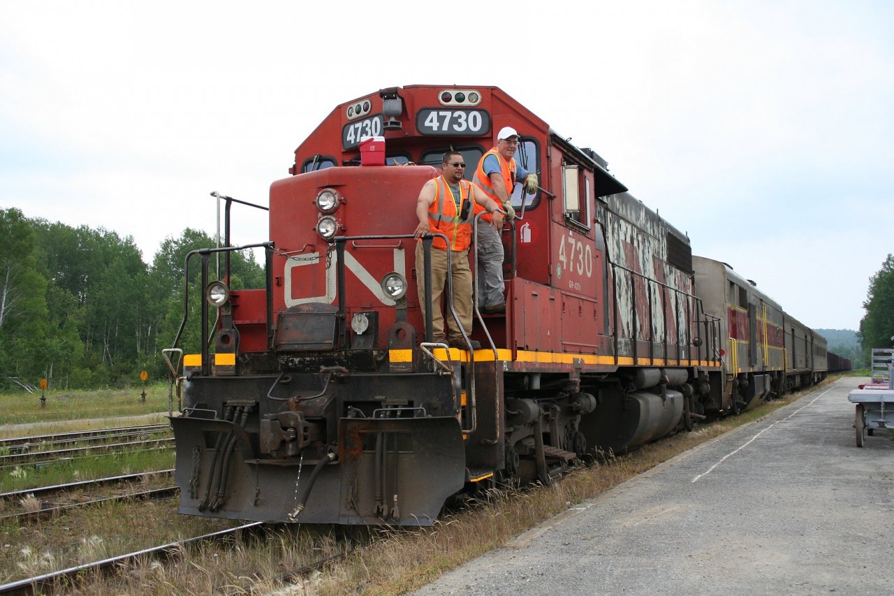 Last run of the "Algoma Spirit" a.k.a. the regular passenger service between Sault Ste. Marie and Hearst on the former Algoma Central Railway.

In the late spring of 2015, the regular passenger service on the former ACR was transferred to new operator RailMark Canada. For a while, trains were operated under RailMark's management using manpower provided by CN paid for and contracted to RailMark while they hired their own crews. In mid June, RailMark took full control of the operation with their own personnel, and almost immediately problems cropped up with the service drastically deteriorating until CN pulled the plug on their relationship with RailMark effective June 15, 2015.

A timeline of RailMark's tenure goes something like this:

January 24, 2014 Local communities are quietly notified that the federal subsidy to the passenger rail service will be cut, and as a result, CN will end operation of the passenger train as of March 31, 2015.

February 14, 2014 CN announces a 4-week extension to April 29, 2014

April 14, 2014 Transport Canada announces a one-year extension to the federal subsidy, to the end of March 2015, in order to give local stakeholders time to evaluate options and propose an alternative solution. Over the next year, a working group is formed to study and lobby for the service, and due to CN's desire to get out of the passenger business, look for alternative operators for the service.

March 31, 2015 On the very last day before CN was slated to discontinue operation, Transport Canada officially announces a new three-year subsidy deal with a new operator, RailMark (although the name of the operator had slipped out about a week earlier when it was revealed they were looking to hire train service personnel in the Sault Ste. Marie area). The funding package is set up in such a way that the city of Sault Ste. Marie will act as trustee to manage the subsidy and have local accountability for the new operator, which has yet to prove their track record - indeed, their record so far seems to consist mainly of other failed tourist trains, a red flag to many, including this photographer. CN will continue to operate the train under the old subsidy agreement until the end of April to give RailMark time to get ready. (It should be noted that RailMark is apparently selected by CN from three qualified bids.)

May 1, 2015 The first day of RailMark's operation of the train, but the train does not run. RailMark's president will cite the lack of a signed agreement yet with the city for the provided funding.  One major pre-condition that the city's Economic Development Corporation has recommended is RailMark being able to prove a certain financial ability to maintain an operation, in the form of appropriate insurance and financing in the form of an available line of credit covering up to three months of operating costs. RailMark has succeeded in obtaining a required operating certificate from Transport Canada and the required insurance but cannot yet show they have the available financing.

May 7, 2015 The first northbound train under RailMark's management leaves Sault Ste. Marie, with only a single passenger as no one knows it is actually running. The agreement is still unsigned, but RailMark goes ahead in good faith. Crews and personnel are provided by CN and paid for by RailMark.

June 16, 2015 The first day of 100% RailMark operation with their own crew. The train apparently makes it as far as Mead (approximately 25 miles south of Hearst) before the crew hits their hours of service limit and the train is halted there.

June 17, 2015 The southbound train does not run at all. Many passengers are left stranded. There are allegations of a rules violation the day before and an investigation. RailMark has only the single crew available, so service is effectively brought to a crashing halt for the duration of the investigation. The crew is apparently cleared of any wrongdoing, but service is disrupted for almost an entire week. The passenger equipment is towed to Sault Ste. Marie by the freight train at some point during the week.

June 22, 2015 At a meeting of the Sault Ste. Marie city council, the EDC recommends not signing the funding agreement with RailMark, as they have still failed to meet the pre-conditions for the agreement, i.e. being able to show adequate operational financing with an available line of credit.

June 25, 2015 The train makes its first run north from Sault Ste. Marie since the disruption, but only as far as Hawk Junction. From this point forward, the train will operate north of Hawk Junction only, providing NO service south of Hawk, and erratic service between Hawk and Hearst, with the train on some days turning at Oba and not running the full way. Eventually CN will announce it is terminating its relationship with RailMark as of July 15.

July 13, 2015 The last northbound train leaves Hawk Junction. It will run as far as Oba and return to Hawk Junction later in the evening. The next day the equipment is brought down to Sault Ste. Marie apparently as a dead head move, bringing passenger service on the ACR to an ignominious end.

I happened to already have vacation in the north planned, and by coincidence it just happened that the day I would be in the Wawa area turned out to be the day of the last run. Here the crew (who unfortunately it would seem would now be out of a job) poses just before departure for a photo by a representative of the local Wawa News, standing to my right.

Shortly after the train departs, a brief but rather wet rainstorm puts an appropriate punctuation to a black day for northern rail transportation.