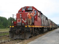 <p>Last run of the "Algoma Spirit" a.k.a. the regular passenger service between Sault Ste. Marie and Hearst on the former Algoma Central Railway.

<p>In the late spring of 2015, the regular passenger service on the former ACR was transferred to new operator RailMark Canada. For a while, trains were operated under RailMark's management using manpower provided by CN paid for and contracted to RailMark while they hired their own crews. In mid June, RailMark took full control of the operation with their own personnel, and almost immediately problems cropped up with the service drastically deteriorating until CN pulled the plug on their relationship with RailMark effective June 15, 2015.

<p>A timeline of RailMark's tenure goes something like this:

<p><b>January 24, 2014</b> Local communities are quietly notified that the federal subsidy to the passenger rail service will be cut, and as a result, CN will end operation of the passenger train as of March 31, 2015.

<p><b>February 14, 2014</b> CN announces a 4-week extension to April 29, 2014

<p><b>April 14, 2014</b> Transport Canada announces a one-year extension to the federal subsidy, to the end of March 2015, in order to give local stakeholders time to evaluate options and propose an alternative solution. Over the next year, a working group is formed to study and lobby for the service, and due to CN's desire to get out of the passenger business, look for alternative operators for the service.

<p><b>March 31, 2015</b> On the very last day before CN was slated to discontinue operation, Transport Canada officially announces a new three-year subsidy deal with a new operator, RailMark (although the name of the operator had slipped out about a week earlier when it was revealed they were looking to hire train service personnel in the Sault Ste. Marie area). The funding package is set up in such a way that the city of Sault Ste. Marie will act as trustee to manage the subsidy and have local accountability for the new operator, which has yet to prove their track record - indeed, their record so far seems to consist mainly of other failed tourist trains, a red flag to many, including this photographer. CN will continue to operate the train under the old subsidy agreement until the end of April to give RailMark time to get ready. (It should be noted that RailMark is apparently selected by CN from three qualified bids.)

<p><b>May 1, 2015</b> The first day of RailMark's operation of the train, but the train does not run. RailMark's president will cite the lack of a signed agreement yet with the city for the provided funding.  One major pre-condition that the city's Economic Development Corporation has recommended is RailMark being able to prove a certain financial ability to maintain an operation, in the form of appropriate insurance and financing in the form of an available line of credit covering up to three months of operating costs. RailMark has succeeded in obtaining a required operating certificate from Transport Canada and the required insurance but cannot yet show they have the available financing.

<p><b>May 7, 2015</b> The first northbound train under RailMark's management leaves Sault Ste. Marie, with only a single passenger as no one knows it is actually running. The agreement is still unsigned, but RailMark goes ahead in good faith. Crews and personnel are provided by CN and paid for by RailMark.

<p><b>June 16, 2015</b> The first day of 100% RailMark operation with their own crew. The train apparently makes it as far as Mead (approximately 25 miles south of Hearst) before the crew hits their hours of service limit and the train is halted there.

<p><b>June 17, 2015</b> The southbound train does not run at all. Many passengers are left stranded. There are allegations of a rules violation the day before and an investigation. RailMark has only the single crew available, so service is effectively brought to a crashing halt for the duration of the investigation. The crew is apparently cleared of any wrongdoing, but service is disrupted for almost an entire week. The passenger equipment is towed to Sault Ste. Marie by the freight train at some point during the week.

<p><b>June 22, 2015</b> At a meeting of the Sault Ste. Marie city council, the EDC recommends not signing the funding agreement with RailMark, as they have still failed to meet the pre-conditions for the agreement, i.e. being able to show adequate operational financing with an available line of credit.

<p><b>June 25, 2015</b> The train makes its first run north from Sault Ste. Marie since the disruption, but only as far as Hawk Junction. From this point forward, the train will operate north of Hawk Junction only, providing NO service south of Hawk, and erratic service between Hawk and Hearst, with the train on some days turning at Oba and not running the full way. Eventually CN will announce it is terminating its relationship with RailMark as of July 15.

<p><b>July 13, 2015</b> The last northbound train leaves Hawk Junction. It will run as far as Oba and return to Hawk Junction later in the evening. The next day the equipment is brought down to Sault Ste. Marie apparently as a dead head move, bringing passenger service on the ACR to an ignominious end.

I happened to already have vacation in the north planned, and by coincidence it just happened that the day I would be in the Wawa area turned out to be the day of the last run. Here the crew (who unfortunately it would seem would now be out of a job) poses just before departure for a photo by a representative of the local Wawa News, standing to my right.

Shortly after the train departs, a brief but rather wet rainstorm puts an appropriate punctuation to a black day for northern rail transportation.