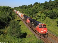 A ES44DC and a DASH 9-44CW are on point of this day's M37231 train with a SD70M-2 locomotive pushing mid-train, en-route to Montreal from Toronto. Yesterday on July 18th of 2015, train Q14921, Montreal - Chicago train derailed on the Kingston Subdivision just east of Oshawa in Bowmanville, with 7 cars propped off the track. No injuries were reported, however this stopped all other trains on the line. The next day when all was cleared up, all the trains that were supposed to be pass by yesterday are now adding up and passing today, including the train in this picture, which is usually seen around the area at about 4-5pm, making this an extremely rare catch in good light.