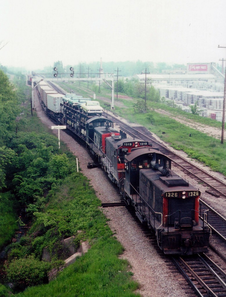 Here's another oldie from your crummy weather specialist. :o) A lot of hazy and humidity noticeable, and I marked my image as this day being 'soupy'.  My initial comment was that this is a prime location for a "Time Machine" follow-up, as it was taken looking east off the Waterdown Rd bridge in Aldershot.......BUT....today I don't think there is a thing left to make comparisons with. This view, believe it or not, today has the Aldershot GO station off out of sight to the left, whilst the trees have been replaced by yard tracks. The Aldershot namesign of course is gone, as is the signal mast; I don't think Cook Concrete is in business on the right side any more; and in place of nothingness in the center of the photo are platforms for commuters. This is quite the scene. CN 1326, 1319 and 7171 with mostly TOFC heading for Hamilton.
