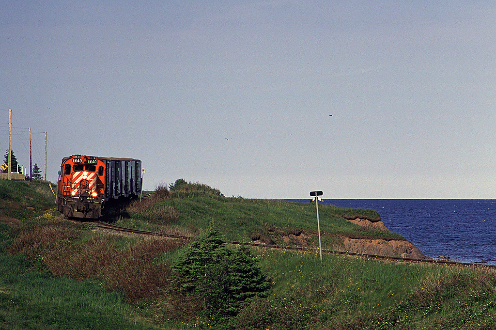 New Brunswick East Coast (former CP Rail) RS18u 1840 leads Chemin de fer Baie des Chaleurs train #593 along the shore of the Baie des Chaleurs. This train ran from New Richmond, QC with an 0600 start to Gaspe to retrieve boxcars loaded with copper anodes. I believe this was the only freight traffic west of New Richmond at the time and sadly is now gone and the line is inactive. This photo is on the return trip to New Richmond. This was a wonderful day to chase a pair of MLWs along a beautiful and scenic line, it was part of a great trip to the area that I shared with my Dad.
