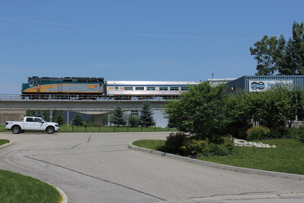 This location is just minutes away from my work so it is a great spot to go to at lunch. VIA 85 is also just minutes from its approximately 12:30 station stop at Kitchener VIA Station. This photo was actually taken at 12:30; however, I'm not sure the exact time it's due in at Kitchener. It has its usually consist of two stainless steel coaches, here glistening from the sun. To the right is TubeFit, where I need to go on occasion for supplies for work. We see it crossing Highway 7, just on the city limits of Kitchener.