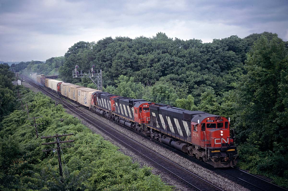 An eastbound freight with 3 big Alcos from MLW coming through Bayview Jct on June 28, 1986 with brake shoes still smoking after descending the escarpment. We thought the setup was kind of odd with the 3 cars in front of the dead-it-tow switcher.  The next time we saw the train on the north side of Toronto (one cloudy shot wasn't going to be enough for this one), the box cars had been set off.