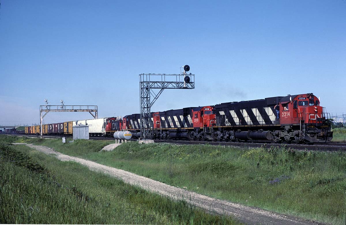 A followup to this posting of the same train at Bayview. http://www.railpictures.ca/?attachment_id=20447
I have the slide labeled as 'North of Toronto".  Pretty sure it is before the train would have entered Mac yard.  Maybe someone will recognize a landmark and fill in the details.  The 3 reefers that were first out behind the power at Bayview had been set off before getting to this point. (and the skies cleared rather nicely)