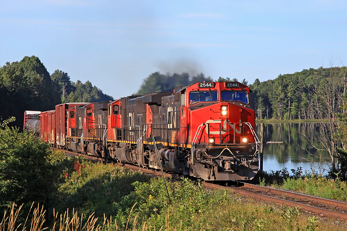 With only two of its four units on line CN 451 approaches the south siding switch at Martins, passing the calm waters of appropriately-named Siding Lake.